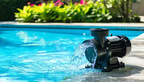 The image captures a detailed closeup of a sleek stateoftheart pool pump system actively circulating water beside a beautifully maintained inground pool The pumps polished surface gleams in the sunlight which dances across the waters surface creating