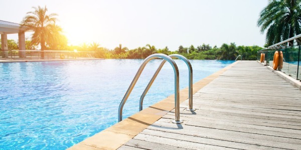 Modern pool with deck and handrail at sunset
